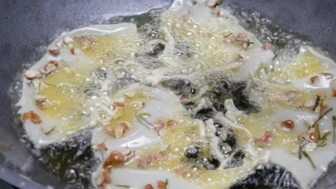Cooking or making peanut crackers in a frying pan with hot oil Stock Footage 304773136