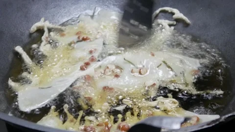 Cooking or making peanut crackers in a frying pan with hot oil Stock Footage 304773168