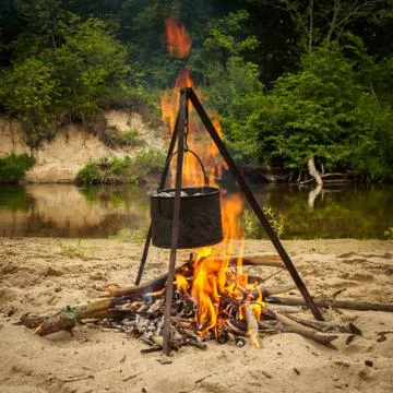 Cooking over a campfire on a trip at the forest river coast. Stock Photos