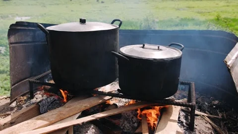 Cooking over a fire in two large pots. The classic method of preparing meal.. Stock Footage 336989804