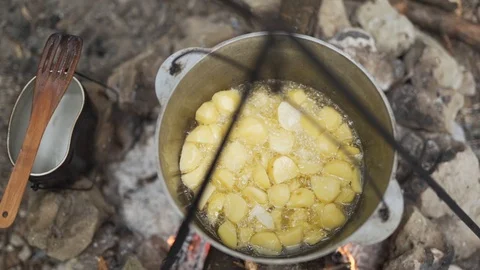 Cooking over open fire on camping trip. Close top down view of food boiling Stock Footage 114308961
