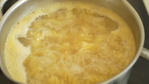 Cooking pasta in pot of boiling water on stove in kitchen. Italian Pasta. Stock Footage 319240370
