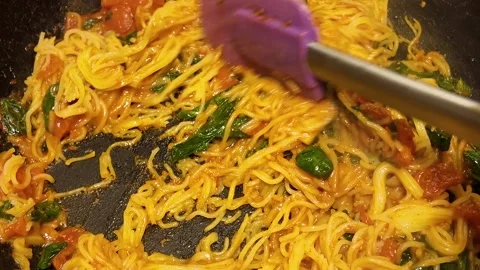 Cooking pasta with tomatoes and spinach in a frying pan Stock Footage 341616923