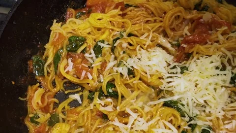 Cooking pasta with tomatoes, spinach and cheese in a frying pan Stockbeeldmateriaal 341616882