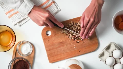Cooking pie at home. Top view woman cuts walnuts on bamboo board. Cooking he 動画素材 247363085