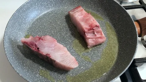 Cooking pieces of greater amberjack, a Mediterranean fish, with olive oil. Stock-Footage 86131153
