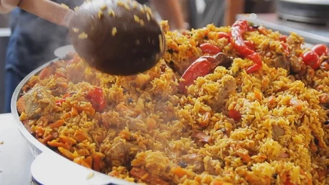 Cooking pilaf in a cauldron. Chef mixing rice with meat and vegetables. Asian Video stock 74591789