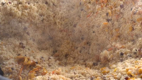 Cooking pilaf in a cauldron. Rice with meat and vegetables. Asian traditional Stock Footage 101796053
