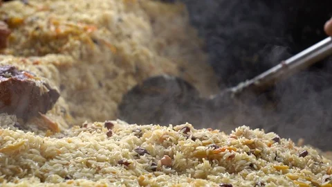 Cooking pilaf in a cauldron. Rice with meat and vegetables. Asian traditional Stock Footage 101802876