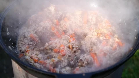 Cooking pilaf in a large cauldron in nature, outdoors. National rice dish. Stock Footage 247713451