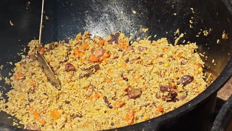 Cooking pilaf in a large pot with meat and rice in a busy kitchen Stock Footage 340461704