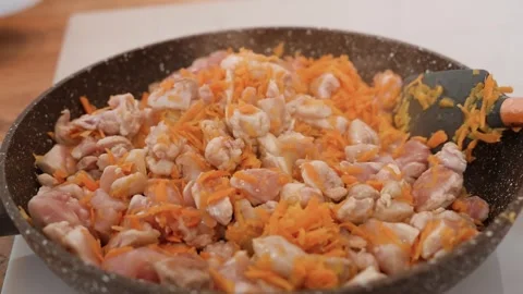 Cooking pilaf, sliced pieces of chicken meat with carrots fried in a frying.. Stock Footage 318463587
