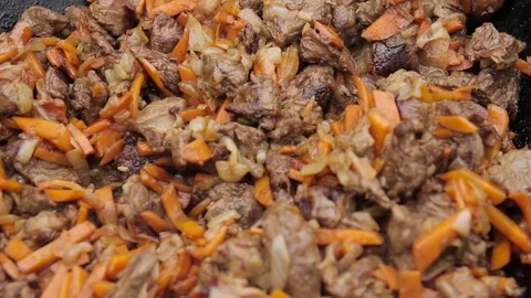 Cooking of pilaff with lamb, carrots and spices onions in a cauldron Stock Footage