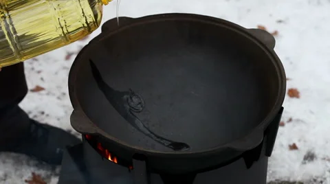 Cooking of pilaff with lamb. The man pouring the sunflower oil into the cauldron 動画素材 63661797