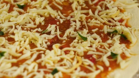 Cooking pizza. Chef put cheese and basil on the base of the pizza greased with Stock Footage 104783175