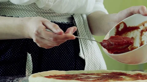Cooking pizza. Female hands adding and spreading tomato sauce on tasty pizza. HD 库存影片 68991643