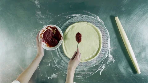 Cooking pizza. Female hands adding and spreading tomato sauce on tasty pizza. HD Stock Footage 69004989