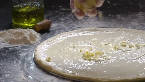 Cooking pizza. Hands adding fresh grated cheese to pizza dough. Pizza Stock Footage 75058604