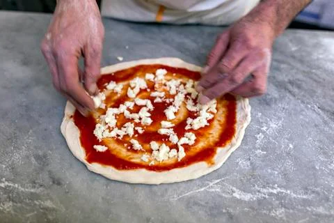 Cooking pizza. Pancake for pizza smeared with tomato sauce lies on the table. Stock Photos