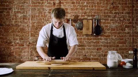 Cooking a pizza. The young chef rolling out a dough with a rolling pin. 4K Vidéo 84786720