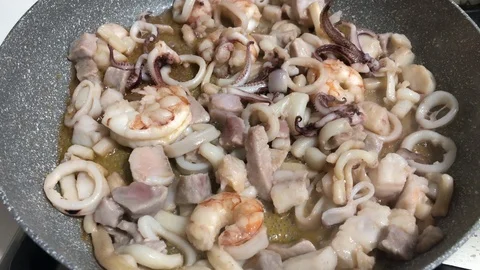 Cooking in a pot a mix of prawns, squids and other fish in olive oil to prepa Stock-Footage 86131174