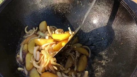 Cooking potatoes in a cauldron at a campfire. Vídeo Stock 155249645