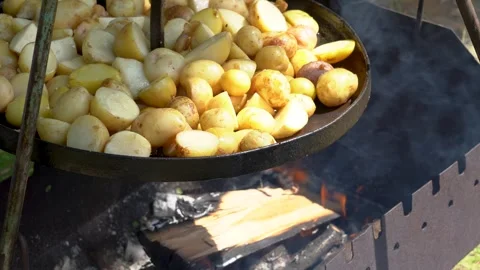 Cooking potatoes over open fire in a backyard grill on a sunny day Video stock 339500553