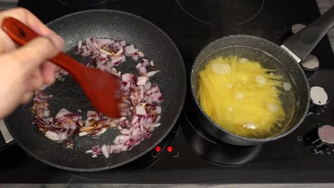 Cooking process. Finely chopped red onions are cooked on the stove and the pa Stock-Footage 162405433