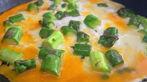 Cooking process of fresh green asparagus pieces being sauteed in a frying pan Stock Footage 340640023