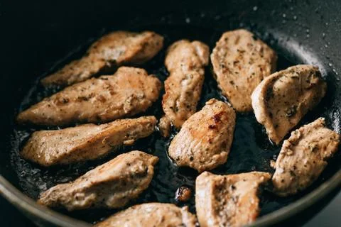 Cooking process. Fried chicken steak in a frying pan. fatty junk food. Stock Photos