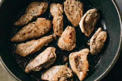 Cooking process. Fried chicken steak in a frying pan. fatty junk food. Stock Photos