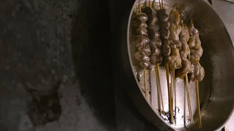 Cooking process of frying meat on sticks in pan at kitchen of asian restaurant Stock Footage 128283747