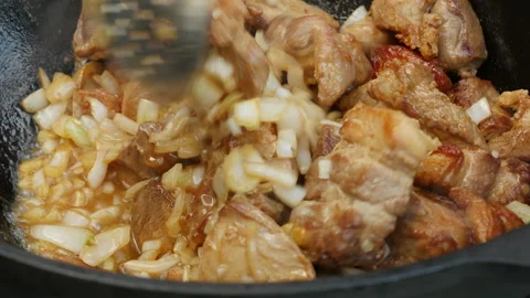Cooking process, frying pork meat and onion in large cauldron on open fire.  스톡 동영상 131646833
