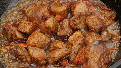 Cooking process, frying pork meat with carrots and onion on open fire Video stock 131647732