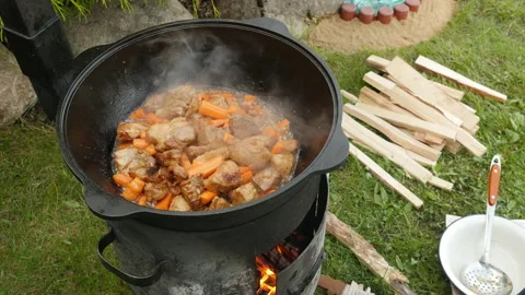 Cooking process, frying pork meat with carrots and onion on open fire. Close up Stock Footage 131671248
