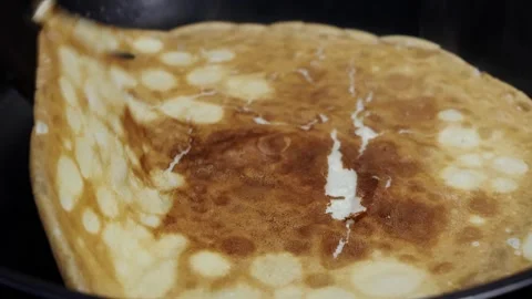 Cooking process of a golden-brown pancake being flipped in a frying pan Stock Footage 331592565