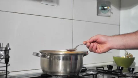 The cooking process, the man's hand takes a sample with a spoon. healthy food Stock Footage 220369637