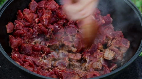 Cooking process of an oriental dish. red meat boils and stews in oil in a large Stock Footage 146554637