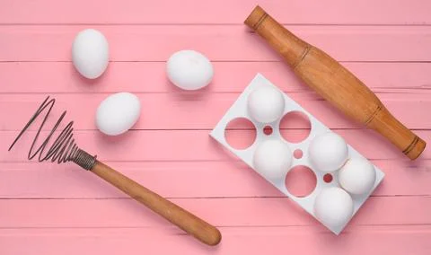 The cooking process. Plastic tray with white eggs, rolling pin, whisk on a pi 写真素材