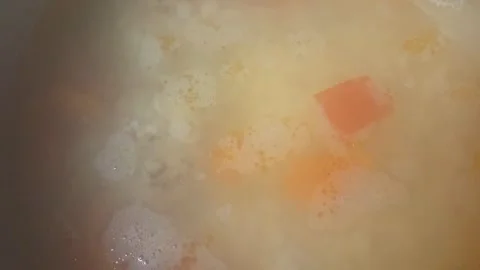Cooking process of vegetable soup with carrots and potatoes simmering in a pot Stock Footage 334306017