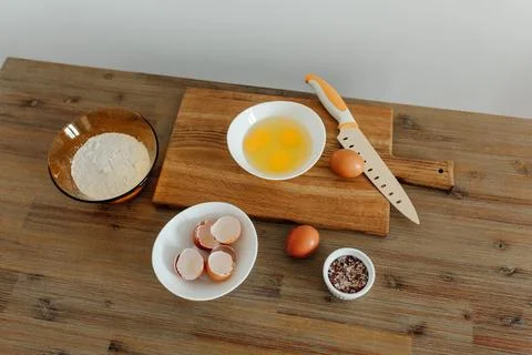 Cooking in progress. Eggs, flour, salt on the table, cutting board and knif.. Stock Photos