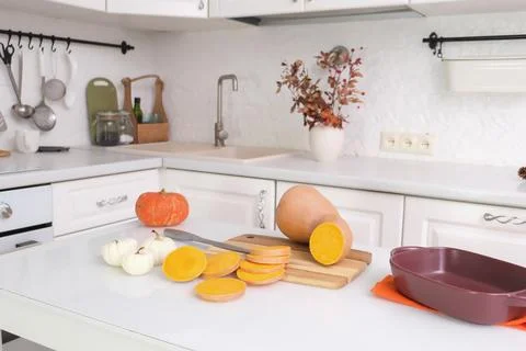 Cooking pumpkin for baking in ceramic dish on wooden board on wooden table in Stock Photos