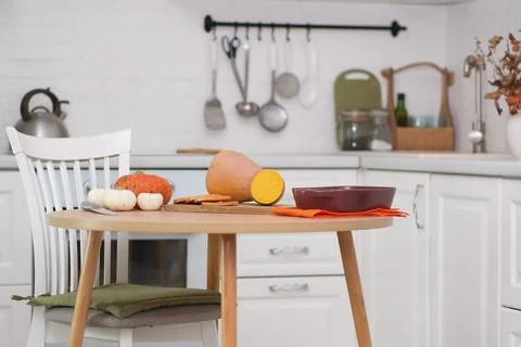 Cooking pumpkin for baking in ceramic dish on wooden board on wooden table in Stock Photos