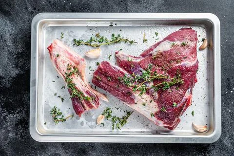 Cooking of Raw lamb mutton leg with thyme, pepper and olive oil in baking tray Stock Photos