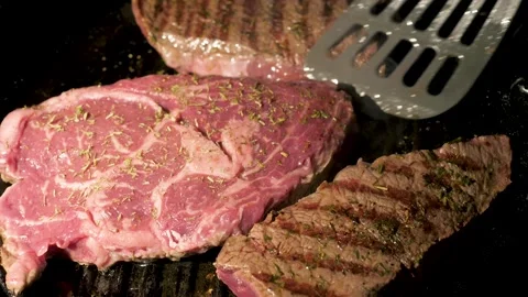 Cooking ribeye close up of steaks developing crust and melting butter Stock Footage 332175020