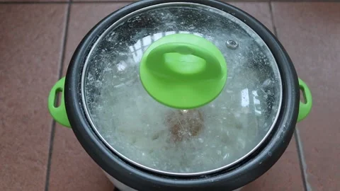 Cooking rice and boiling eggs in electric rice cooker on tile flooring Stock Footage 144478282