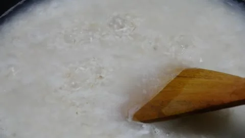 Cooking rice in a black pan, stirring using a wooden spatula Stock Footage 304721839