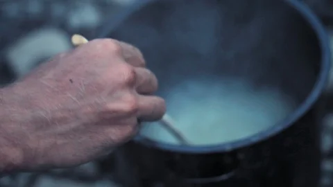 Cooking rice in a pot while hand with wooden spoon stirs the boliling water. 스톡 동영상 116913176