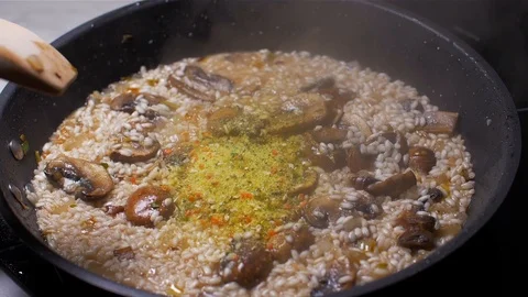 Cooking risotto with mushrooms and adding  dry broth powder. Slow motion Stock Footage 103632028