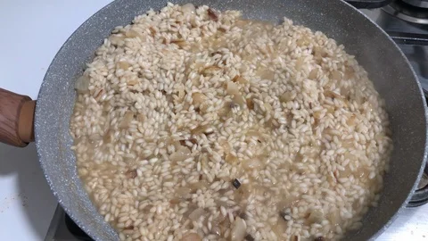 Cooking risotto, a typical Italian rice cooked with onions and broth. Stock-Footage 85717831
